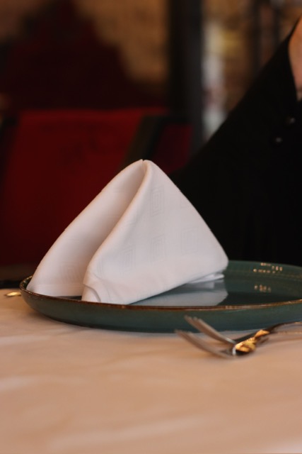 Folded white napkin on a plate, table detail