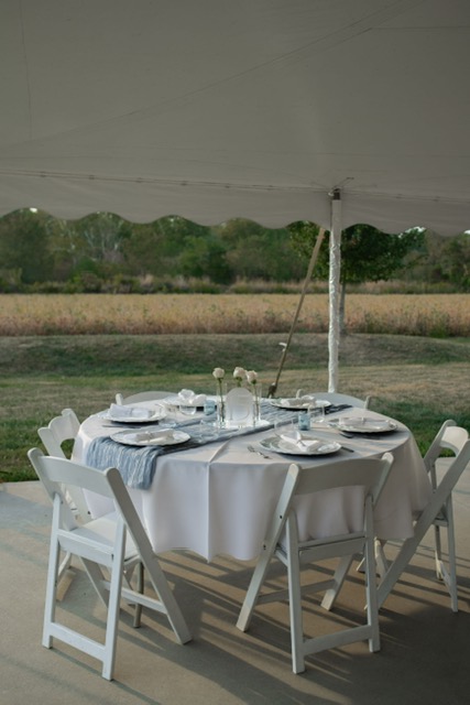 Rows of white folding chairs set for an outdoor ceremony under a covered patio